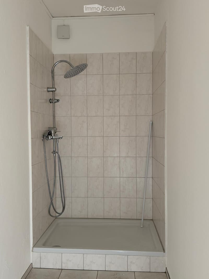 Modern bathroom with a bathtub, tiled walls, and a showerhead with a handheld sprayer.