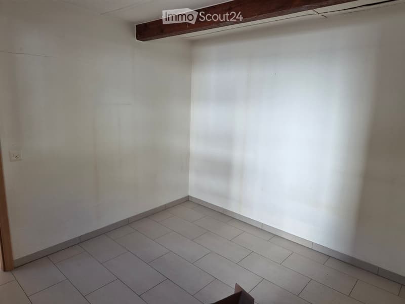 Empty room with white walls, tiled floor, and a wooden door frame. No furniture or equipment present.