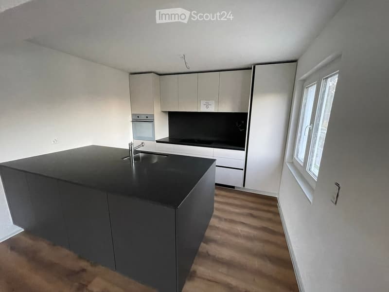 Modern kitchen with a black island, white cabinets, and a stainless steel sink and faucet.