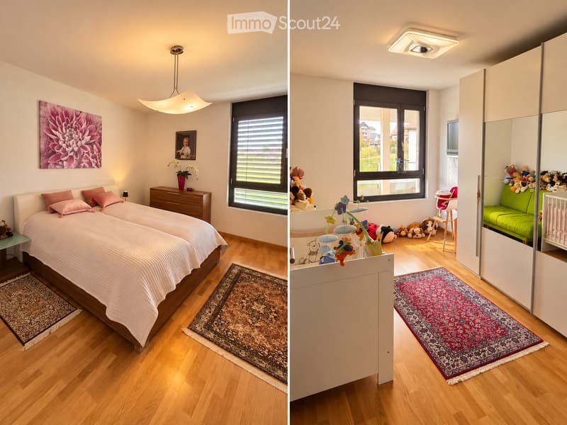 Two connected rooms: a bedroom with a bed, nightstand, and picture frame, and a living area with a green sofa, baby chair, and toys. Both rooms have wooden flooring and large windows.