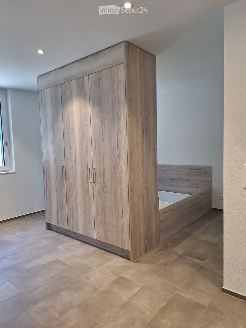 {"visible_features": [], "type": "Room", "description": "Empty room with large built-in wardrobe, wooden bed, hardwood floors, white walls, window with white frame."}