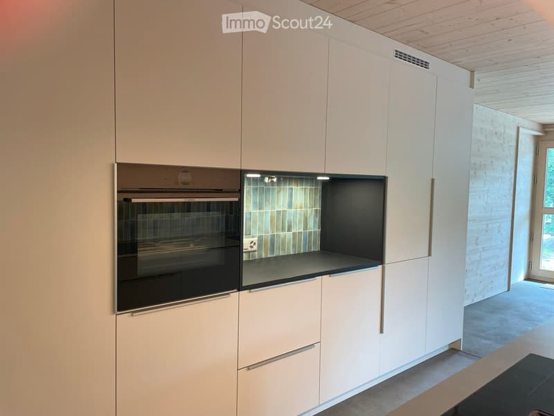 Modern kitchen with white cabinets, a built-in oven, and a sleek countertop.