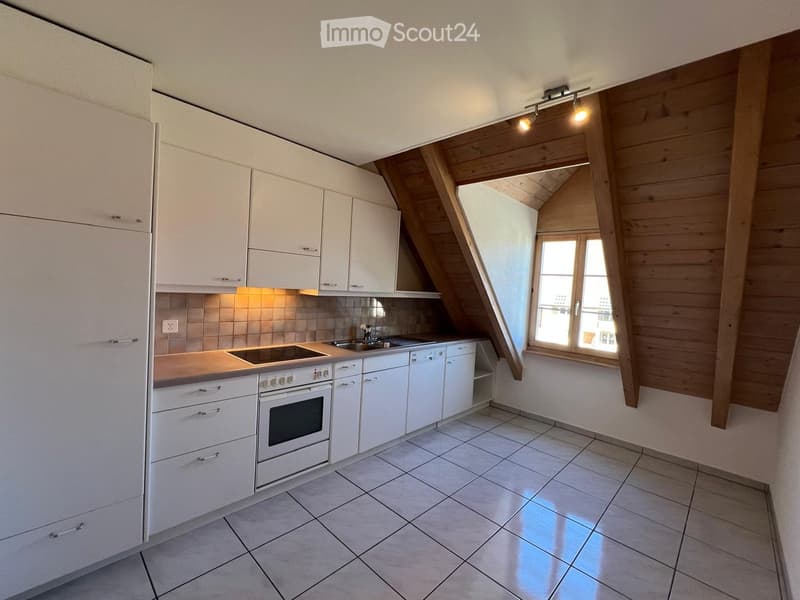 Modern kitchen with white cabinets, stainless steel appliances, and a large window with wooden trim. The space features a tiled floor and a sleek, contemporary design.