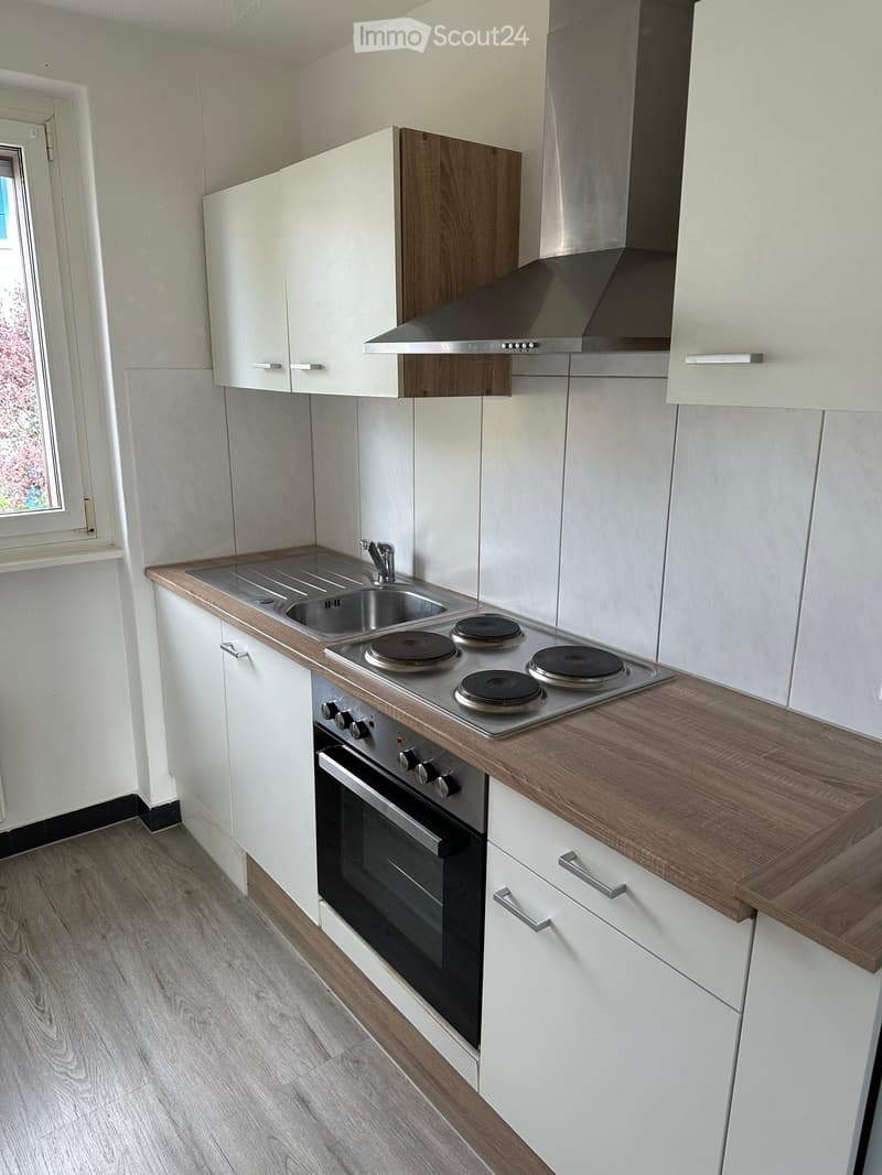 Modern kitchen with white cabinets, wooden countertops, stainless steel sink, induction cooktop, and built-in oven.