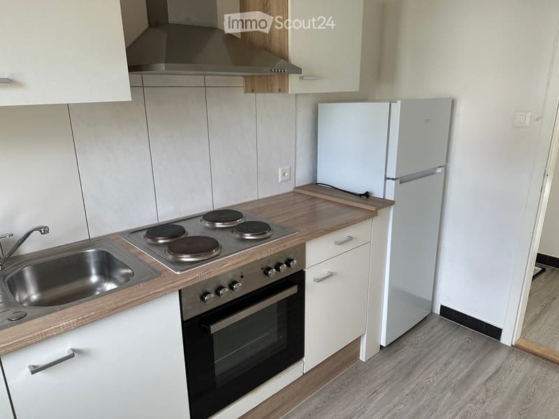 Modern kitchen with white cabinets, wooden countertops, stainless steel sink, induction cooktop, oven, and refrigerator.