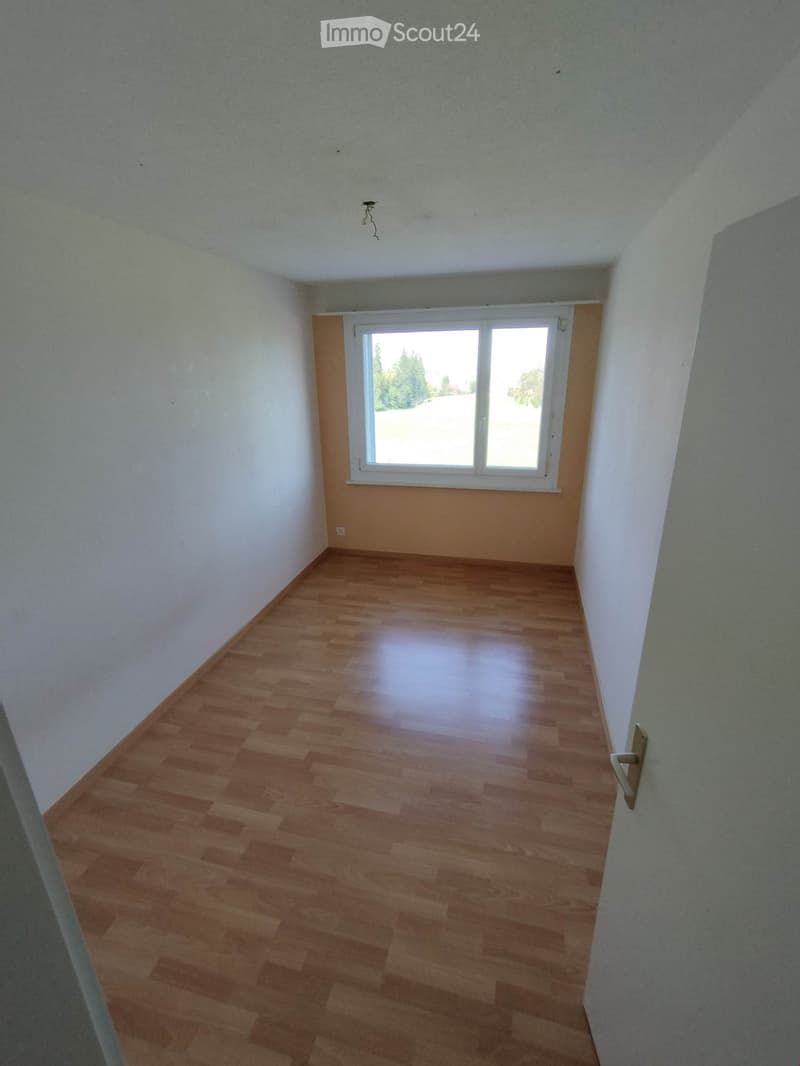 Empty room with wooden flooring, white walls, and a large window with white frame. No furniture or equipment present.