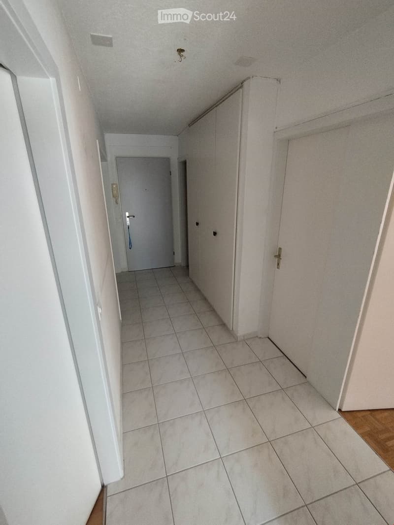Empty hallway with tiled floor, white walls, and doors on both sides.