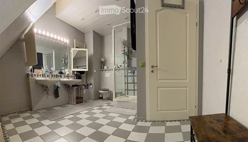 Modern bathroom with checkered floor, double sink, large mirror, shower stall, and toilet.