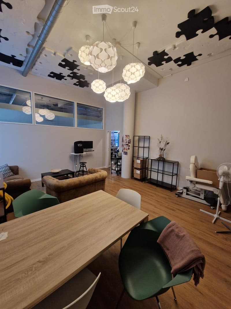Modern living space with wooden flooring, large windows, pendant lights, a sofa, a coffee table, a dining table with chairs, and a fan.