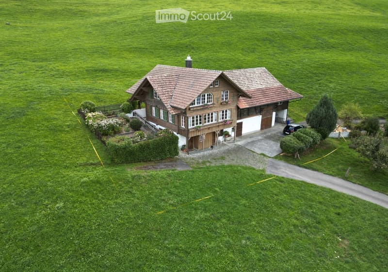 A two-story house with a tiled roof, surrounded by a well-maintained lawn and garden, featuring a garage and a driveway.
