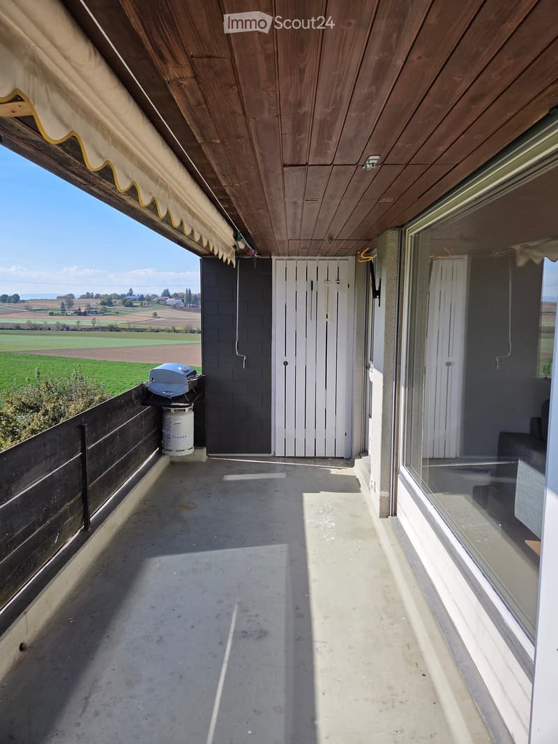 Balcony with wooden ceiling, concrete floor, and scenic countryside view.