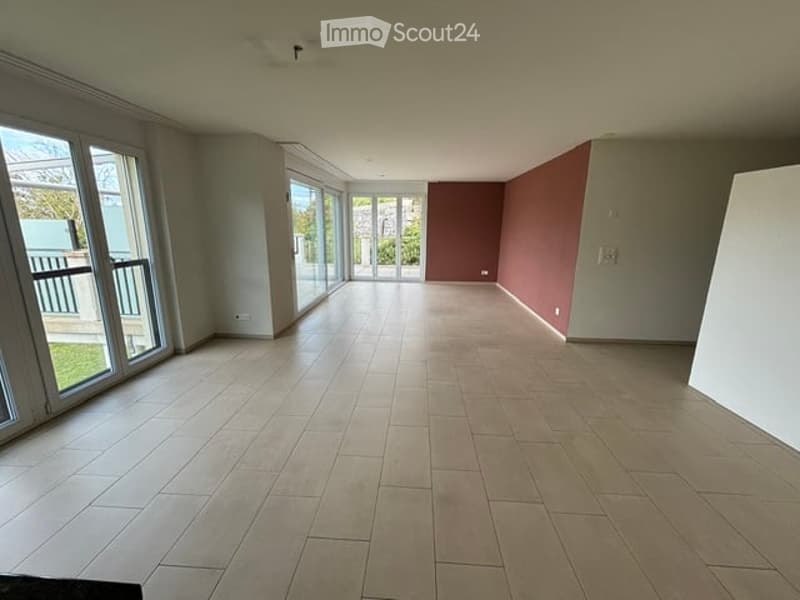 Empty room with tiled flooring, large windows, and sliding glass doors leading to a balcony.