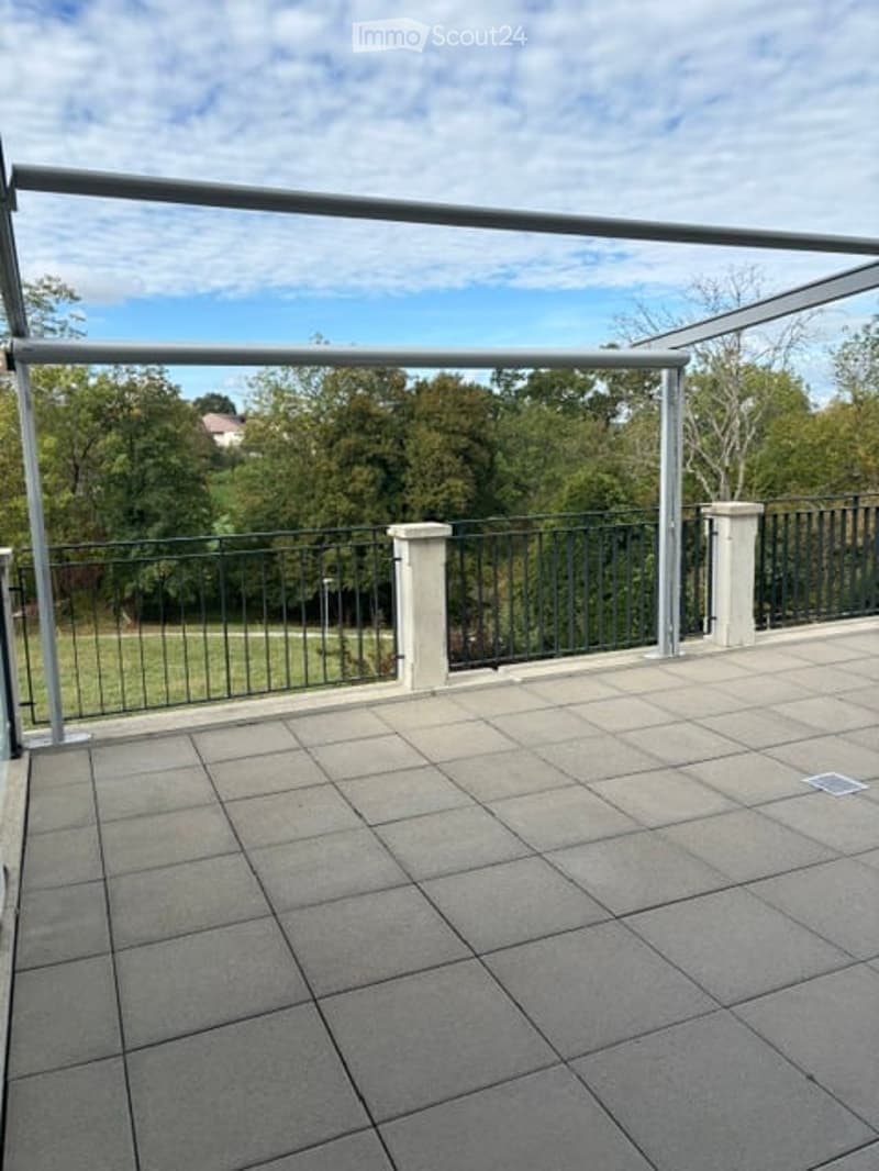 Balcony with tiled floor, metal railing, and a view of a green park.