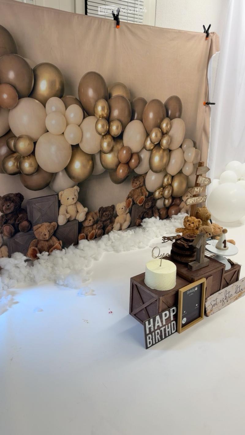 A festive birthday setup with balloons, teddy bears, a cake, and decorative signs.