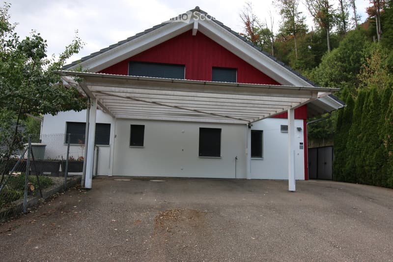 Two-story house with red and white exterior, featuring a covered driveway and multiple windows.
