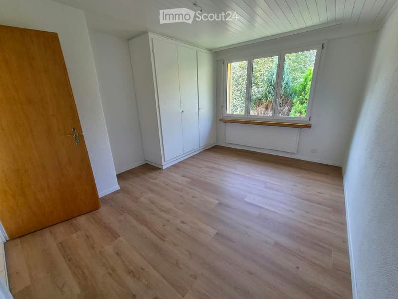Empty room with wooden flooring, white walls, large windows, and built-in white closet units.