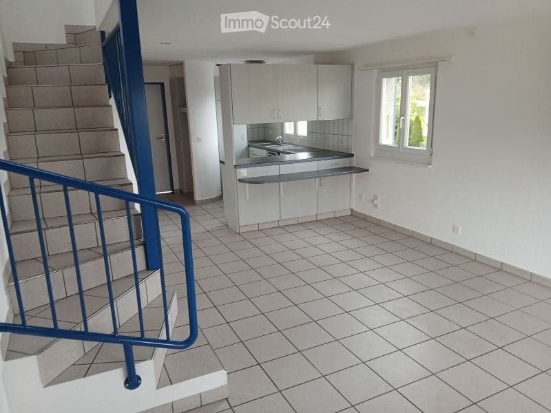 Empty kitchen with white cabinets, tiled floor, and a window. No furniture or appliances are present.