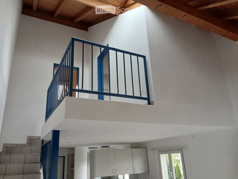 Open staircase leading to a balcony with blue railings, white walls, and wooden ceiling beams.