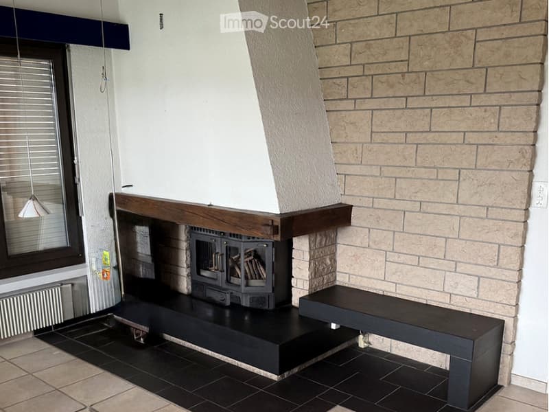 Modern living room with a stone fireplace, black bench seating, and a hanging light fixture.