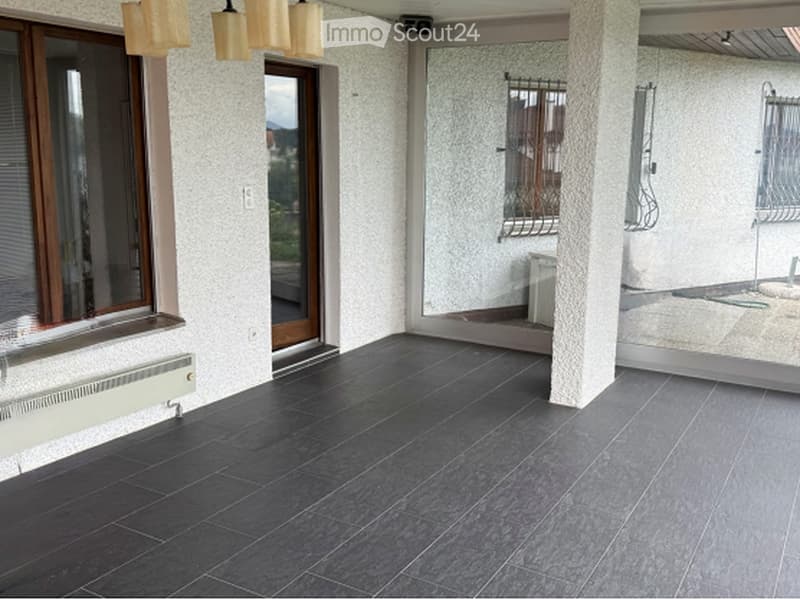 Balcony with dark grey tiled flooring, large windows, and a view of the outdoors.