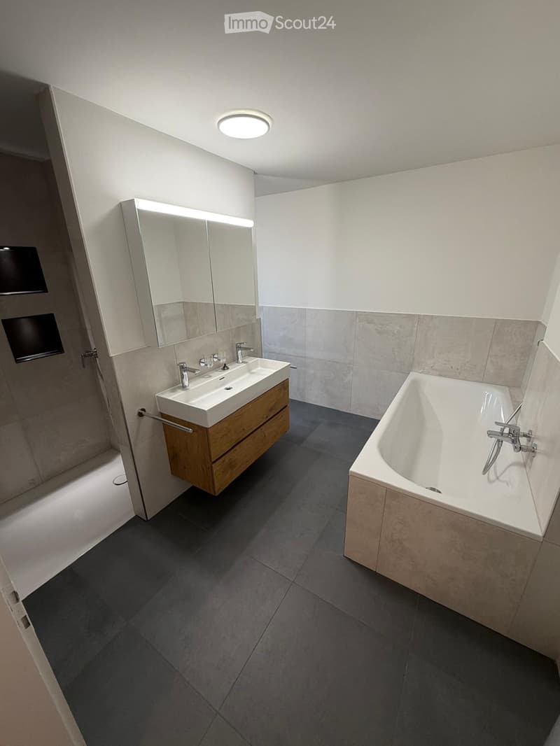 Modern bathroom with a freestanding bathtub, double sink vanity with wooden cabinet, large mirror, and sleek fixtures.