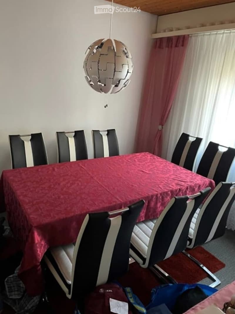 Dining table with red tablecloth, 8 chairs, pendant lamp, curtains