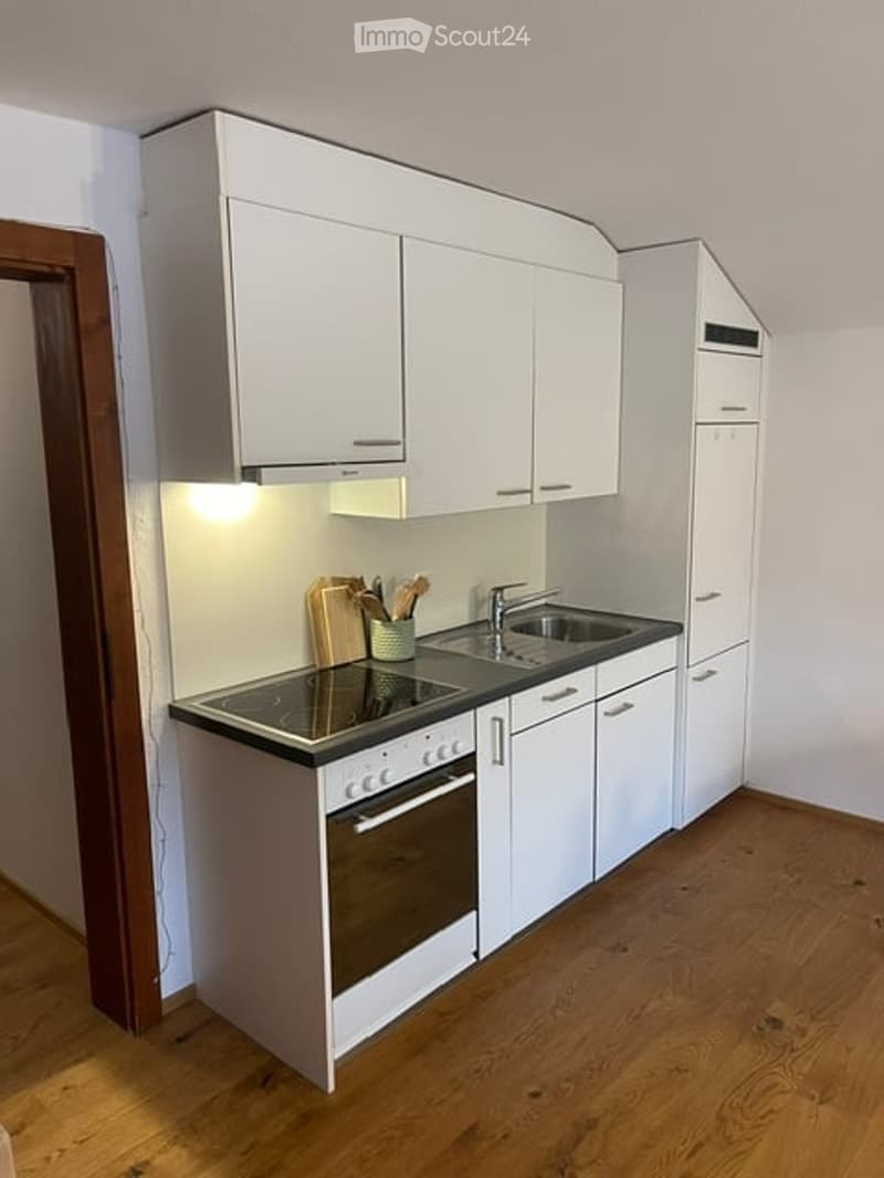 Modern kitchen with white cabinets, a built-in oven, a sink with a faucet, and a countertop with a cutting board and utensils.