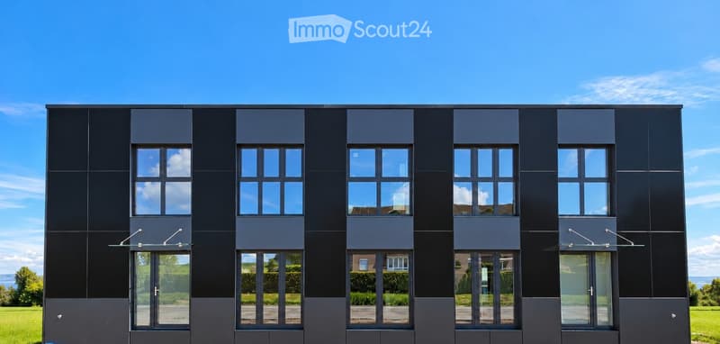 Modern two-story building with dark gray facade, large windows, and glass entrance doors.