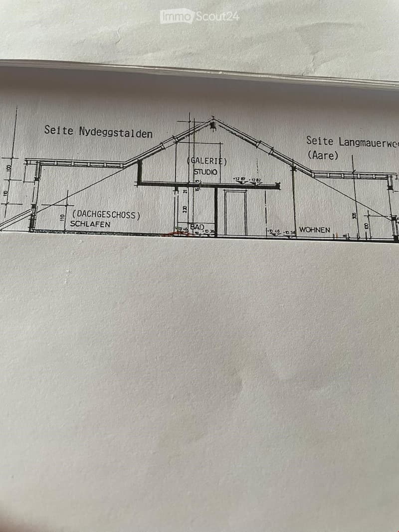 Floor plan showing a multi-level structure with labeled areas: Dachgeschoss (attic), Schlafzimmer (bedroom), Bad (bathroom), Wohnen (living area), Galerie (gallery), and Studio.