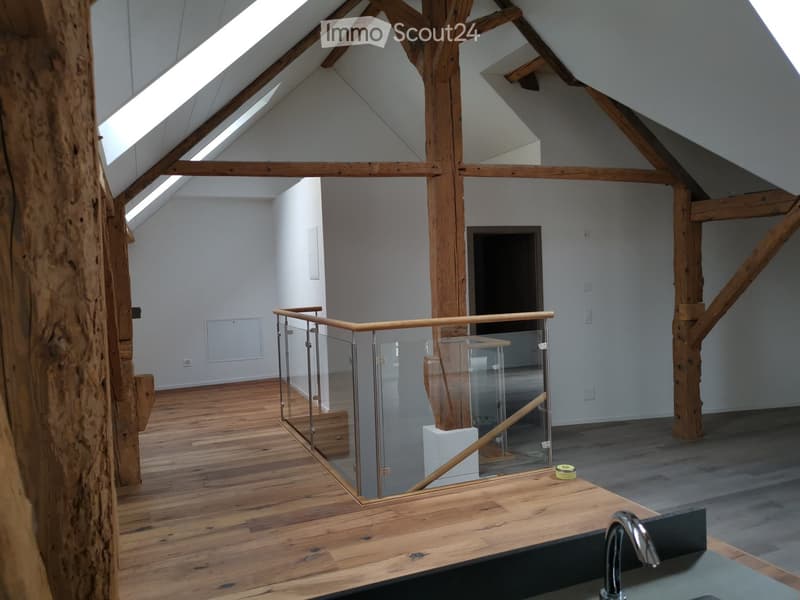 open space with glass railing, wooden beams, wooden floor, glass panels, skylight
