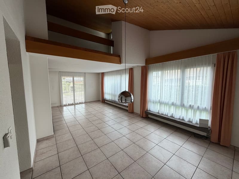Empty room with tiled floor, large windows with sheer curtains, and a hanging spherical light fixture.