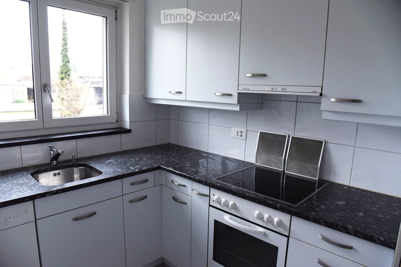 Modern kitchen with white cabinets, granite countertops, stainless steel sink, and built-in appliances including an oven and stove.