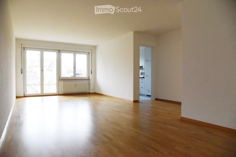 Empty room with wooden flooring, large windows, and a radiator. The space is unfurnished with no visible furniture or equipment.