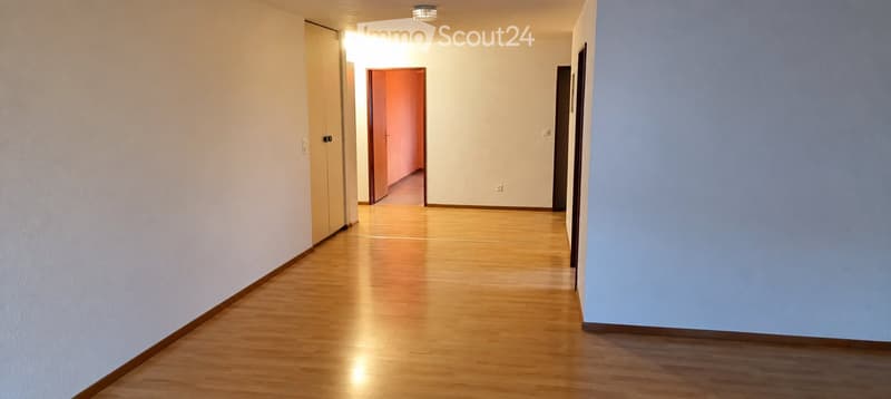 Empty hallway with wooden flooring, white and blue walls, and several doors leading to other rooms.