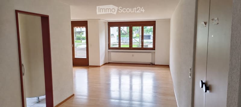 Empty hallway with wooden flooring, white walls, and large windows. No furniture or equipment present.