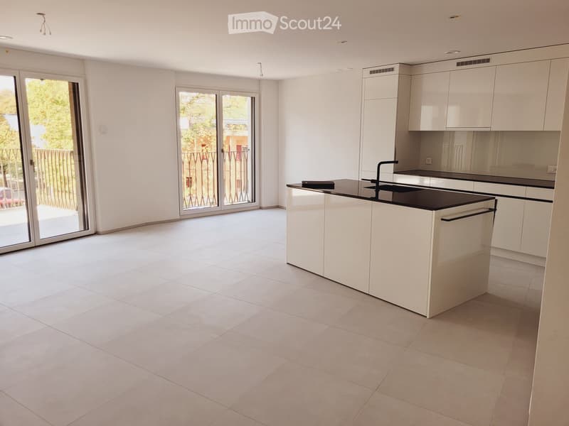 Modern, unfurnished kitchen with white cabinets, a central island, and large sliding glass doors leading to an outdoor area.