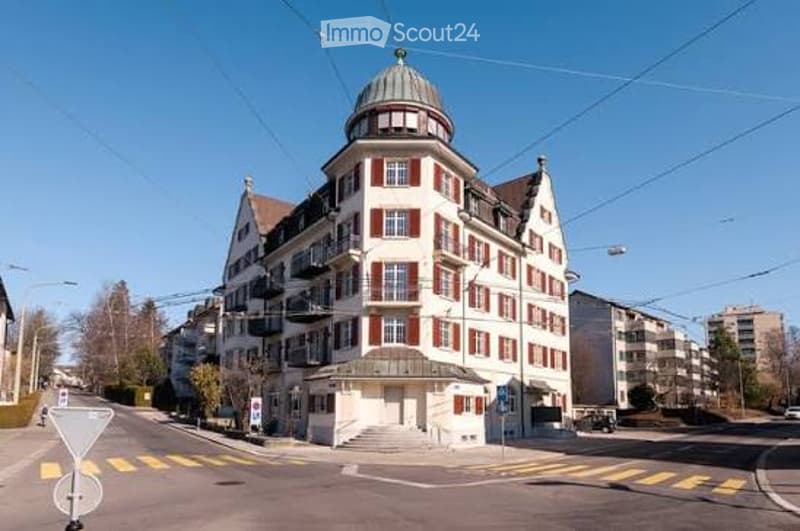 Multi-story residential building with red and white facade, arched windows, and a domed roof section.