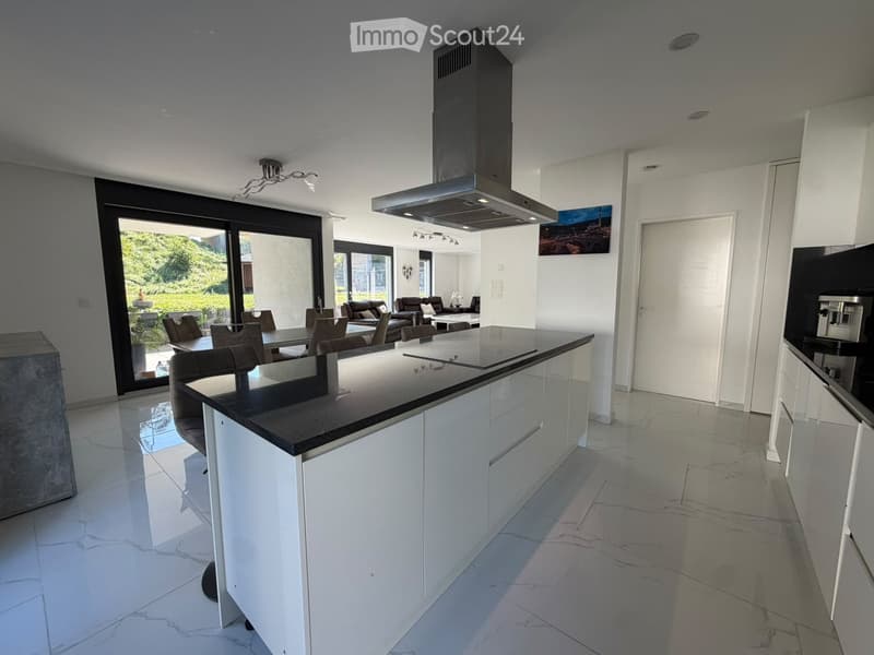 Modern kitchen with white cabinets, a central island, and a dining area connected to a living space with a sofa and coffee table.