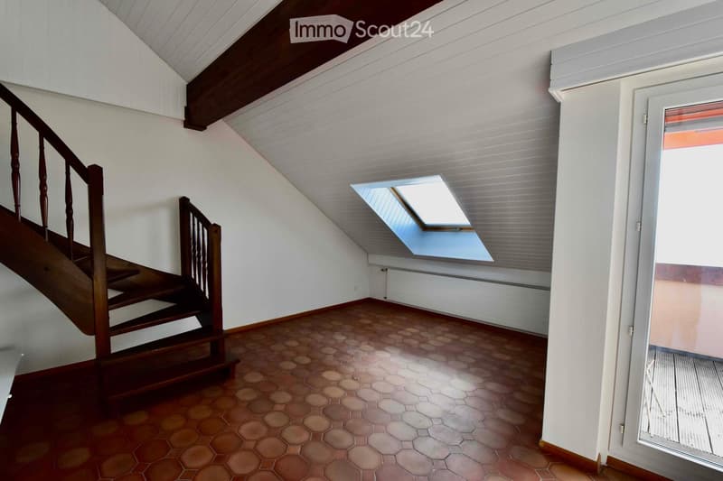 Empty attic room with wooden staircase, skylight windows, and hexagonal tiled floor.