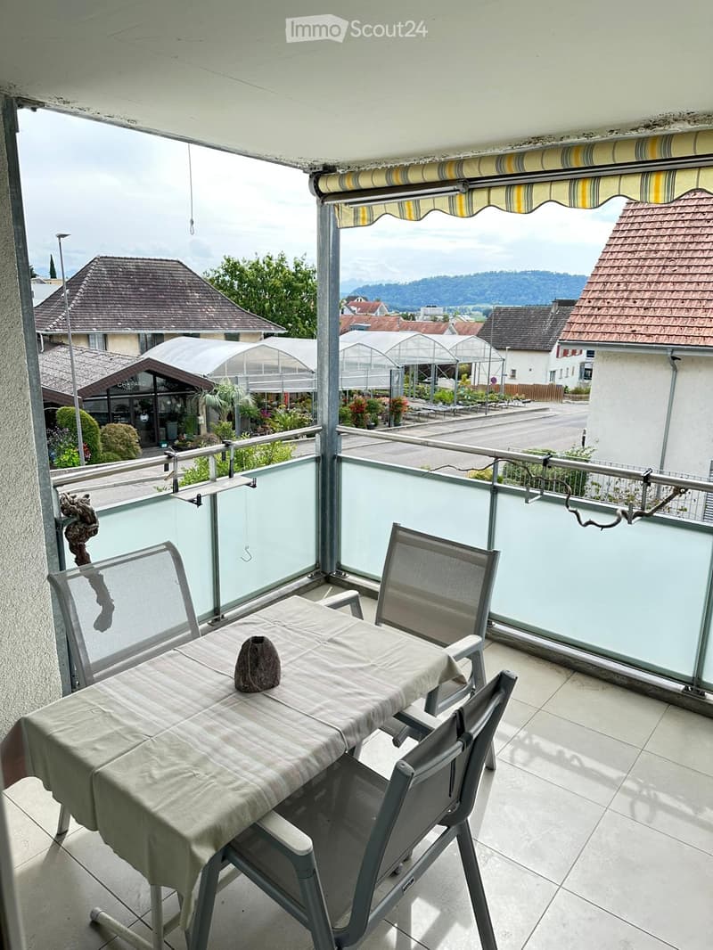 Balcony with a table, chairs, and a view of the surrounding area.
