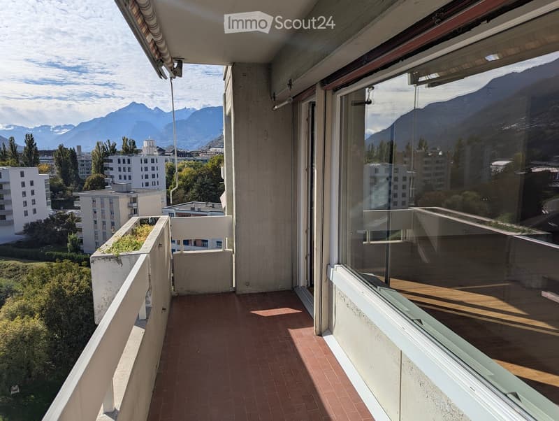 Balcony with red tiled floor, glass railing, and scenic mountain view.