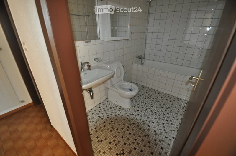 Bathroom with white tiles, a sink, toilet, bathtub, and a mirrored cabinet above the sink.