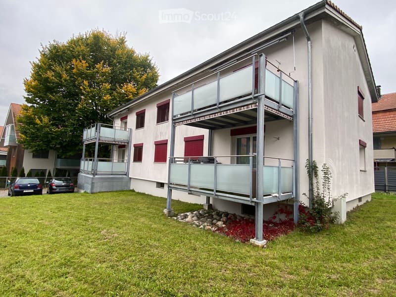 2 story building, 2 balconies, red shutters, white exterior, tree, cars parked