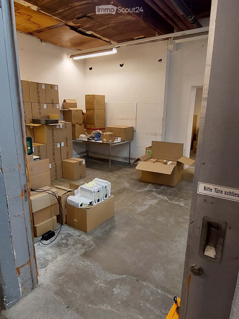 Empty room with concrete floor, white walls, and scattered cardboard boxes and a small table with items on it.