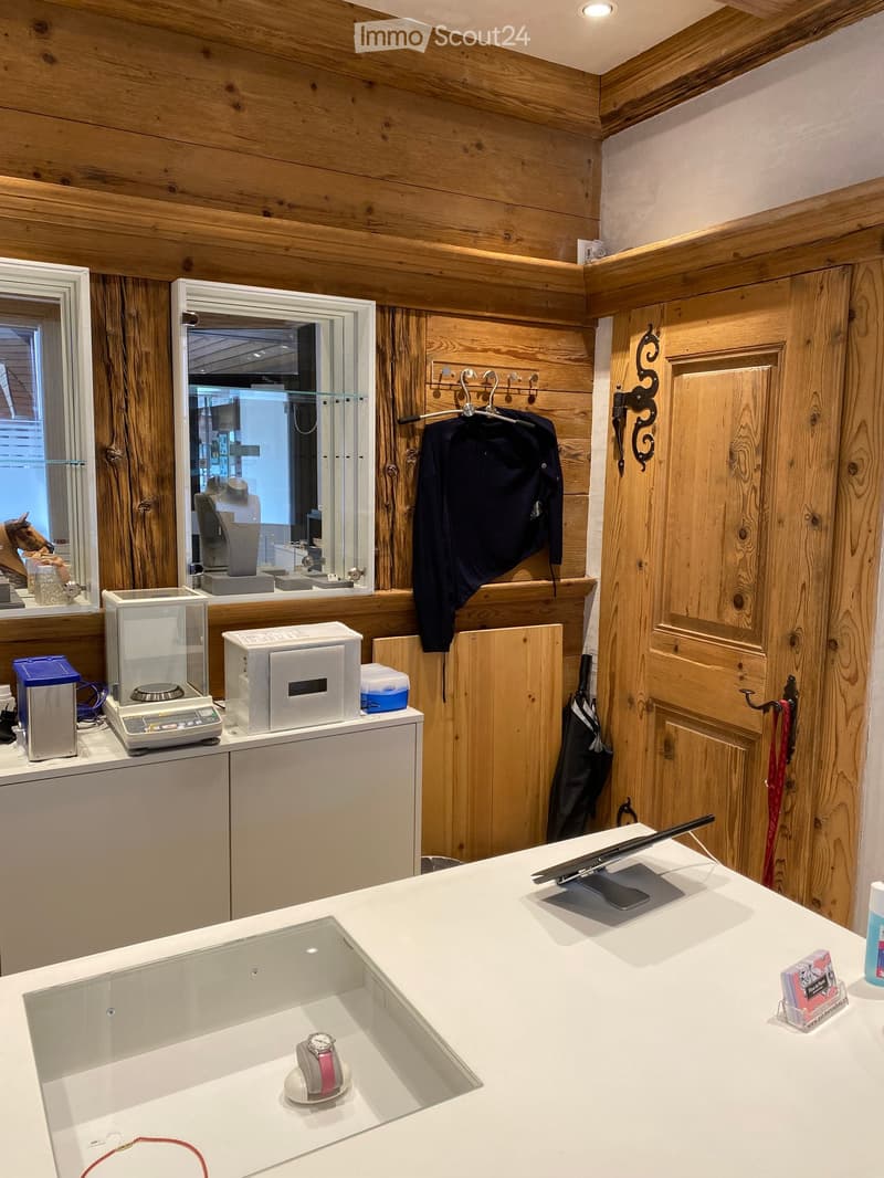 A well-organized jewelry store counter with a scale, mirror, display cases, and various jewelry items. Wooden walls and a modern design.