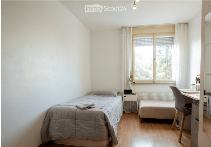 Cozy bedroom with a single bed, nightstand, desk, chair, and a window with curtains.
