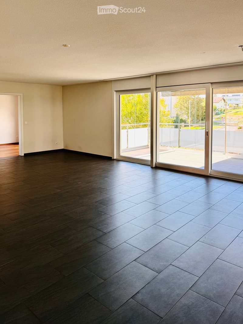 Empty room with dark wooden flooring and large sliding glass doors leading to a balcony area.