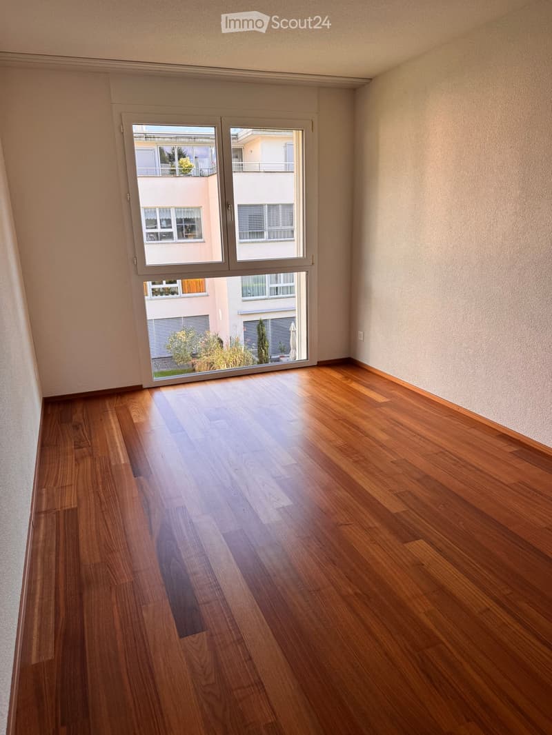 Empty room with wooden flooring and large sliding glass doors leading to a balcony or outdoor area.