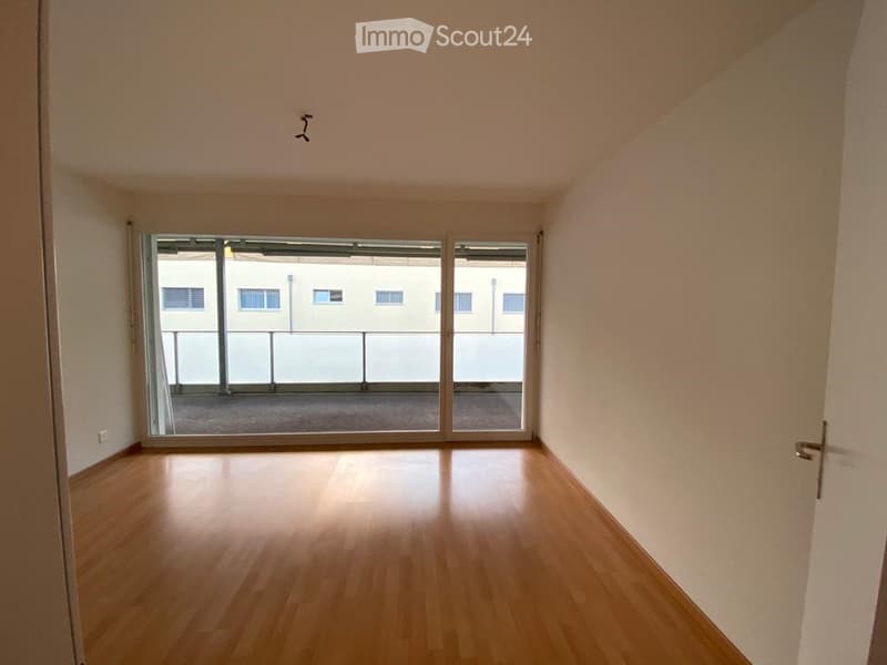 Empty room with wooden flooring, large sliding glass doors leading to a balcony or terrace area.