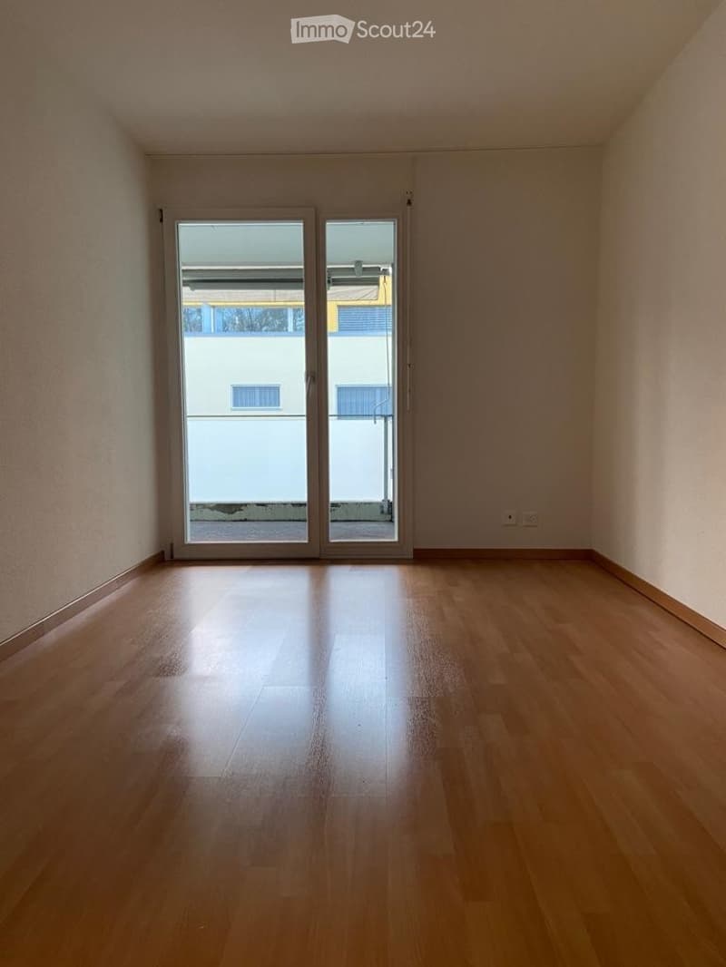 Empty room with wooden flooring and large sliding glass doors leading to an outdoor area.
